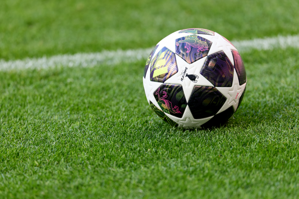 Imagem da bola oficial da Champions League em um gramado de futebol